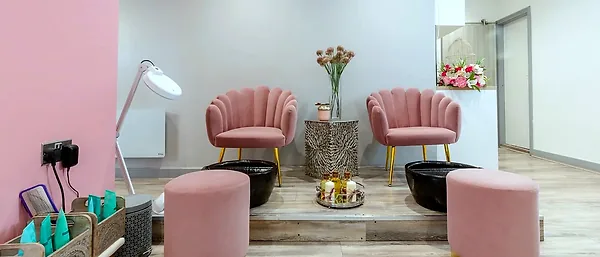 Two pink velvet pedicure chairs either side of a table of dried flowers
