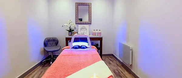 The beauty room: a treatment couch under an LED light therapy lamp, with an orchid and candles
